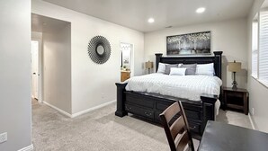 A bedroom with a bed, bedside tables, a chair, a wall clock, and a door. - Mountain Escape in Eden, Utah (Eden)