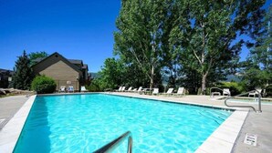 A rectangular swimming pool with clear blue water, surrounded by lounge chairs and a building with a sloped roof in the background. - Mountain Escape in Eden, Utah (Eden)