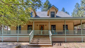 A two-story house with a covered porch and a small front yard. - 1-acre retreat with firepits, wraparound porch & a relaxing 6-person hot tub (Sisters)