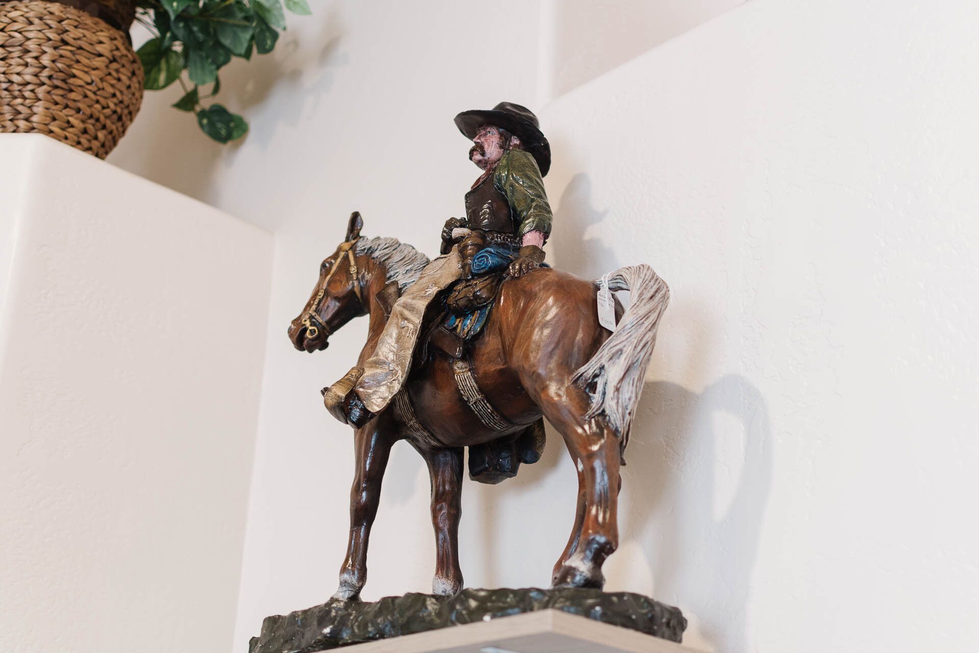 A wooden sculpture of a man on a horse, mounted on a stone base.