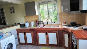A kitchen with a wooden island, a microwave, a sink, and a stove. - Joss plein  air (Le Gosier)