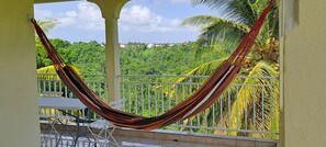 A hammock on a balcony with a view of lush greenery and houses in the distance. - Joss plein air (Le Gosier)