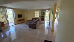 A spacious living room with a sofa, coffee table, and TV. - Joss plein  air (Le Gosier)