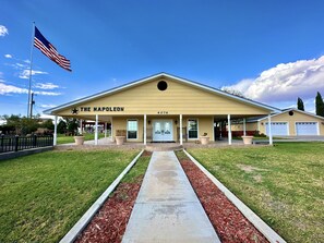 A building named "The Napoleon" with a flagpole, a covered porch, and a driveway. - The Napoleon (Fort Stockton)