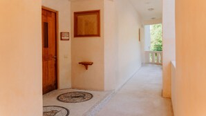 A hallway with a wooden door, a small shelf, and a framed picture on the wall. - Pacífica Grand Zihuatanejo (Zihuatanejo)