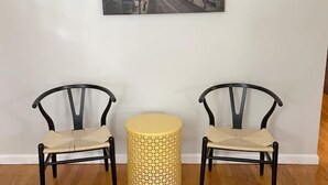 A room with two black chairs and a round yellow table against a white wall.