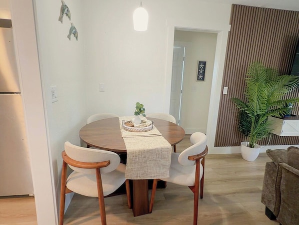 Comedor con una mesa redonda, cuatro sillas, una planta pequeña y una lámpara.