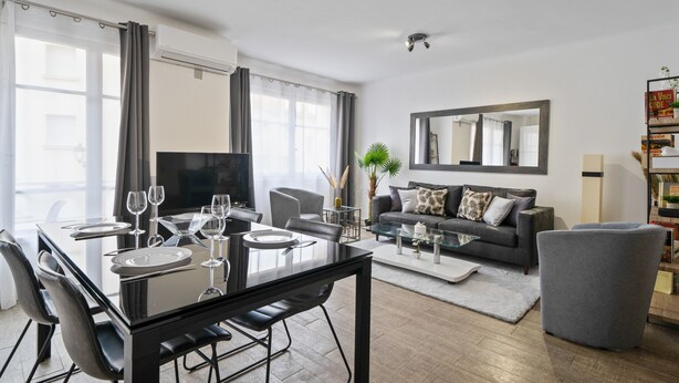 Una sala de estar moderna con comedor, un sofá, una mesa de centro y un televisor.