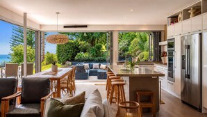 A modern kitchen with a view of lush greenery and the ocean.