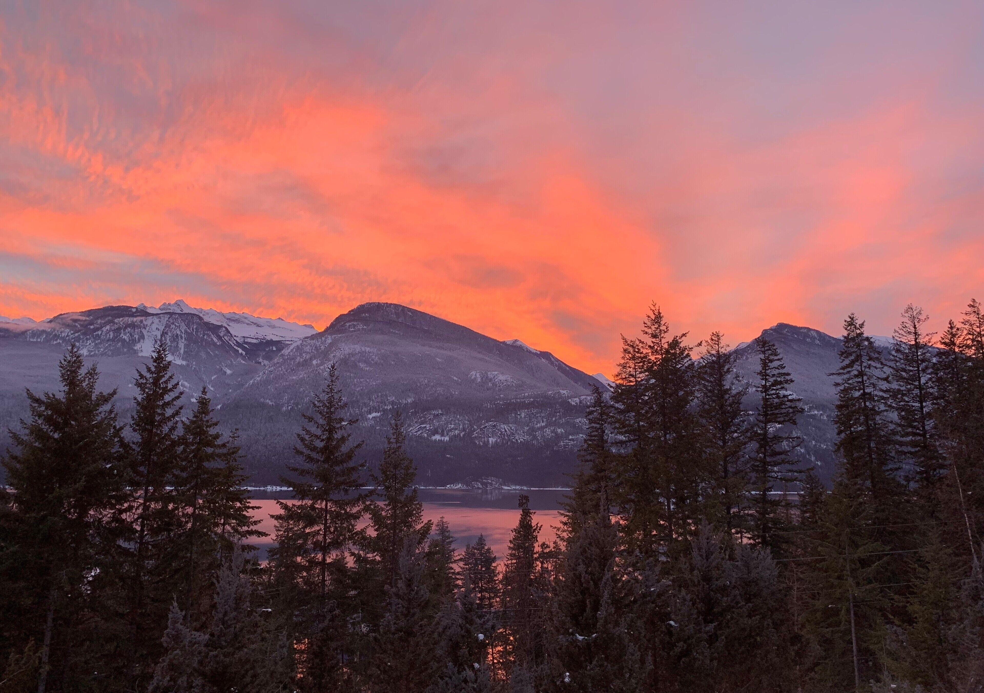 Un paysage montagneux avec des sommets enneigés et un lac qui reflète le ciel.
