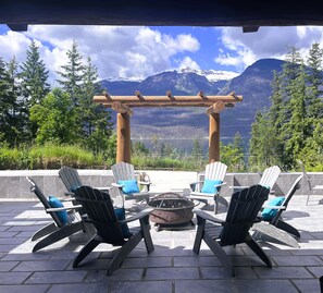 An outdoor seating area with Adirondack chairs and a fire pit, overlooking a mountainous landscape. - New Denver Lodge (New Denver)