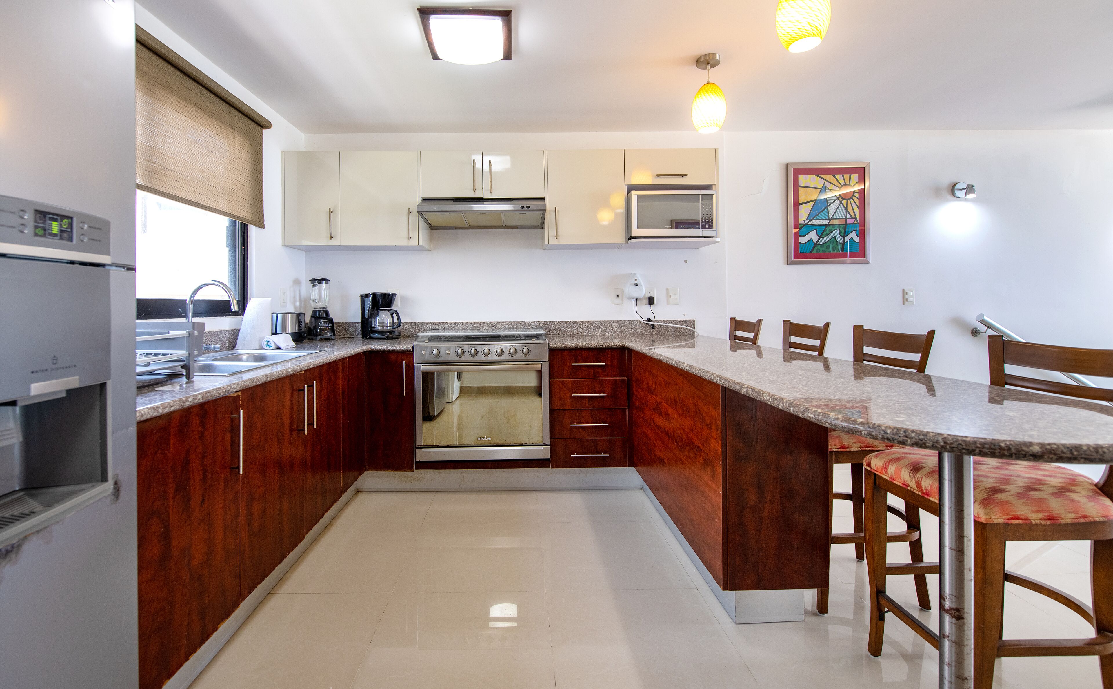 Una cocina con gabinetes de madera, estufa, microondas y cafetera.
