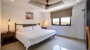 Ein Schlafzimmer mit einem Bett, Nachttischen, einem Deckenventilator, einem Fenster mit Blick und Kunstwerken an der Wand.
