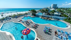 Resort com várias piscinas, acesso à praia e palmeiras.