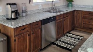 A kitchen with wooden cabinets, a stainless steel dishwasher, a coffee maker, and a sign that reads "Coffee Farmhouse". - Bryce Canyon Cottage! Just a few of mins away. (Panguitch)