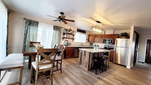 A spacious kitchen with wooden flooring, a central island, and a dining area with wooden chairs and a table. - Bryce Canyon Cottage! Just a few of mins away. (Panguitch)