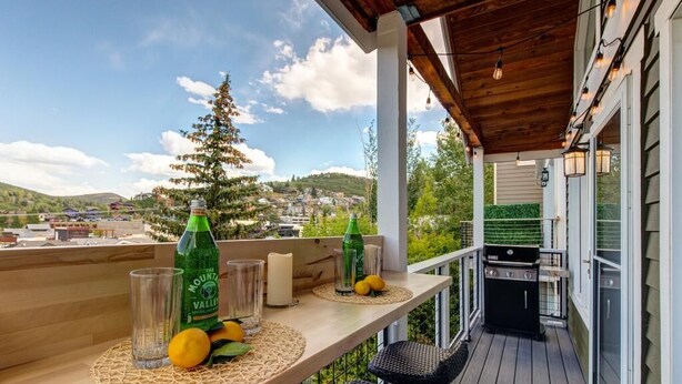 Eine Holzdielen-Terrasse mit Grill, Flaschen Mountain Valley Spitfire, Gläsern und Zitronen.