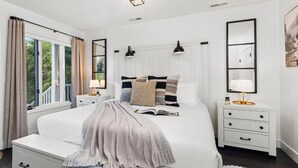Ein Schlafzimmer mit einem großen Bett, Nachttischen, einem Vorhangfenster und einem Spiegel an der Wand.