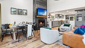 Ein modernes Wohnzimmer mit Kamin, Essbereich und Küche.