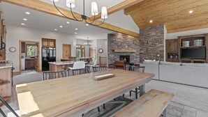 A spacious living area with a large wooden dining table, a stone fireplace, and a cozy seating area. - New to Market Private Weber River Access Stunning Family Retreat (Morgan)