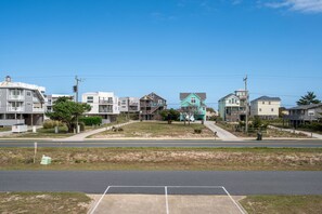 A residential street with houses, a clear sky, and a road with a parking lot.