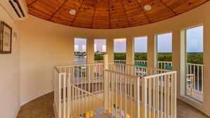 Un balcón espacioso con techo de madera y barandilla blanca, que ofrece vistas del paisaje circundante.