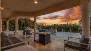 Un espacio al aire libre cubierto con piscina, asientos y vistas al atardecer.