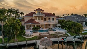 Una casa grande con piscina, muelle y jardín tropical.