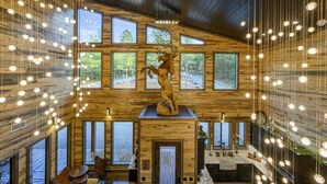 Un intérieur spacieux avec des murs en bois, de grandes fenêtres et une sculpture en bois au centre.