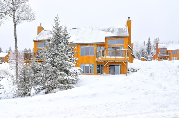 A multi-story wooden building with a balcony, surrounded by snow-covered trees.