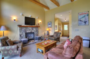 A cozy living room with a stone fireplace, comfortable seating, and a mounted television. - Saddleback - Black Gnat Condo #12 (Sandy River Plantation)
