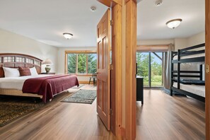 A bedroom with a bed, a desk, a chair, a bunk bed, and a large window.