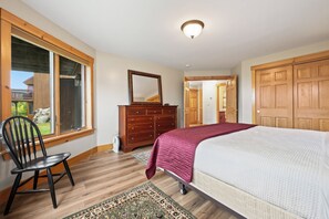 A bedroom with a bed, dresser, chair, and a large window. - Saddleback - Black Gnat Condo #12 (Sandy River Plantation)