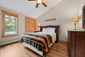 A bedroom with a bed, a window, a ceiling fan, a wooden door, and a wall-mounted sign. - Saddleback - Black Gnat Condo #12 (Sandy River Plantation)