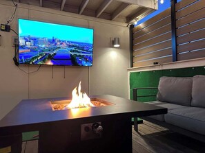 A modern living room with a flat-screen TV mounted on the wall, a built-in fire feature, and a green accent wall. - Rooftop Townhouse w/ Game Room, 2 mi to Downtown (Nashville)