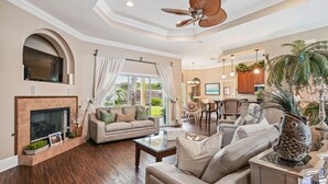 A spacious living room with a fireplace, comfortable seating, a dining area, and a kitchen in the background. - 🐬Destiny East Luxury Home~Golf Cart~Close to the Beach~Five O'Clock Somewhere🐬 (Destin)