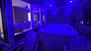 A room with a brick wall, a window, a round table, and a ceiling fan. - Luxe | Hot Tub | Firepit | Heat Floors | EV | Walk2Matthews (Matthews)