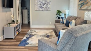 Ein modernes Wohnzimmer mit einem grauen Sofa, einem Couchtisch und einem großen abstrakten Gemälde an der Wand.