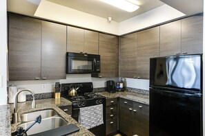 Een moderne keuken met donkerhouten kasten, een roestvrijstalen spoelbak, een magnetron, een fornuis en een koelkast.