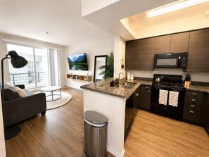 A modern apartment with a kitchen, living area, and a large window. - Sunnyside Up! Gorgeous Pool View with Balcony (Marina del Rey)