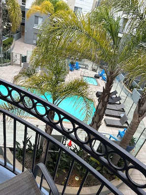 Un espace piscine aménagé sur le toit, avec des chaises longues et des palmiers.