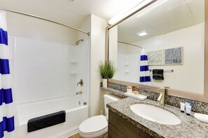 A bathroom with a bathtub, toilet, sink, and a large mirror. - Sunnyside Up! Gorgeous Pool View with Balcony (Marina del Rey)