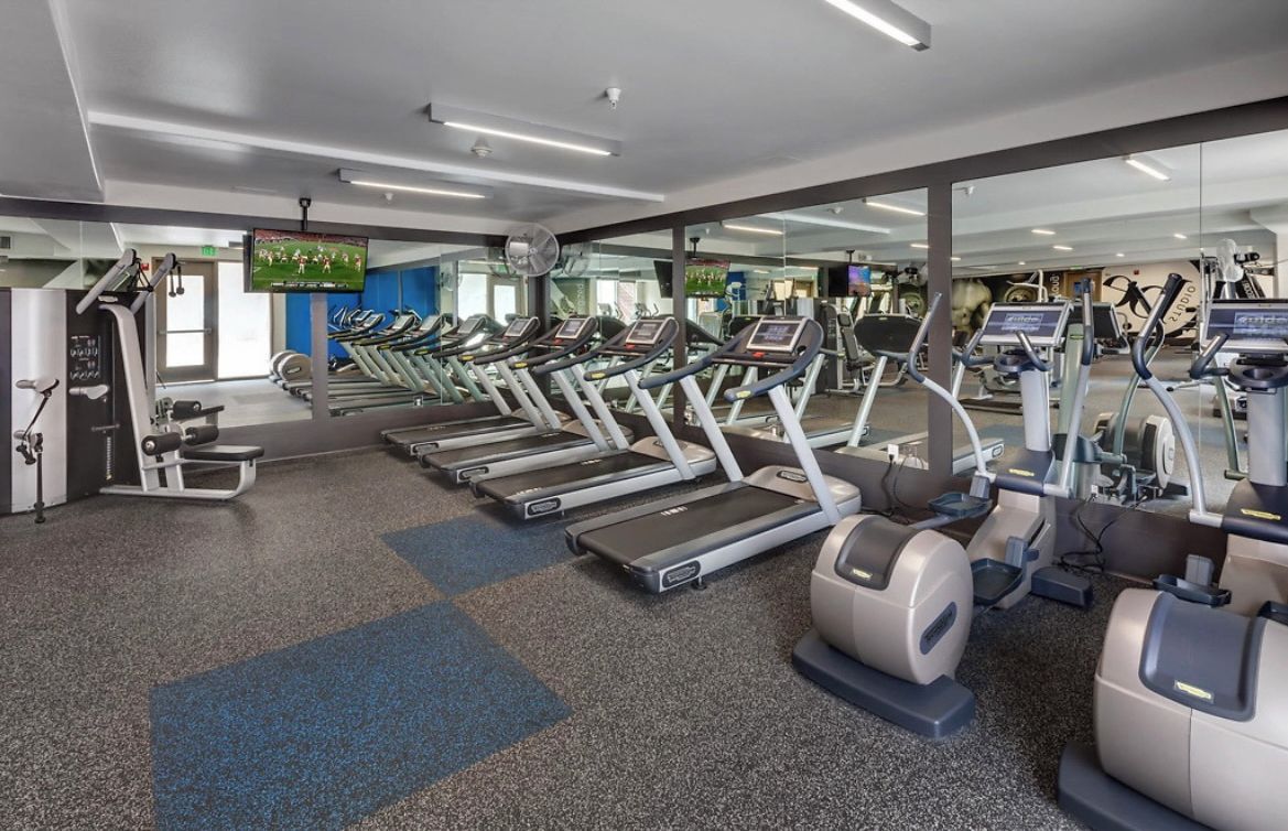 A gym with multiple treadmills, exercise bikes, and weight machines.