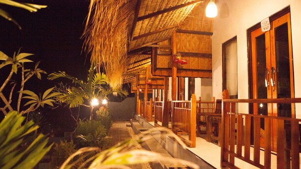 A traditional wooden building with a thatched roof, a covered outdoor seating area, and a visible entrance. - Dayuh House (Penida Island)