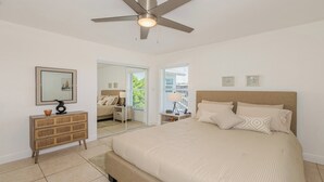 Un dormitorio con una cama grande, un ventilador de techo, un aparador y un espejo.