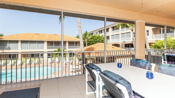 Un balcon avec vue sur la piscine, un espace salon extérieur et une vue sur le bâtiment de l’hôtel.