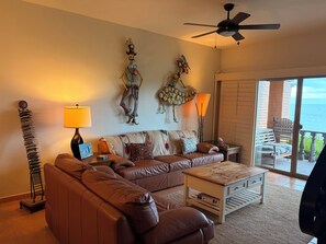 A living room with a brown leather sofa, a coffee table, and a ceiling fan.