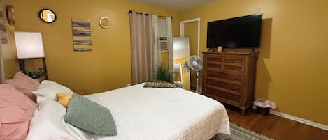 Un dormitorio con cama, cómoda, televisor y espejo.
