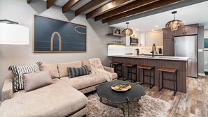 A modern kitchen with a central island, bar stools, and a refrigerator.