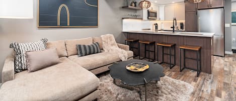 A modern kitchen with a central island, bar stools, and a refrigerator.